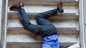 Business man falling down set of stairs.